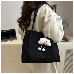 Detail of black tote bag with grid texture featuring a plush white cloud charm accessory