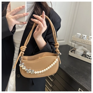 Detail of khaki crescent bag featuring silver heart charm and white pearl chain strap