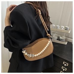 Detail of khaki saddle bag with pearl heart chain and knotted rope shoulder strap detail