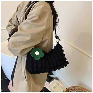 Détail du sac d'épaule noir à texture bulle avec charme fleur verte et bandoulière