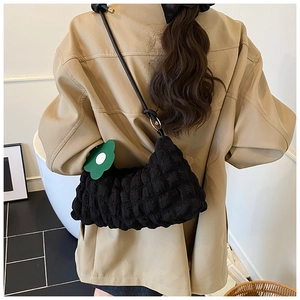 Détail du sac sous le bras noir à texture bulles avec pendentif fleur verte et sangle