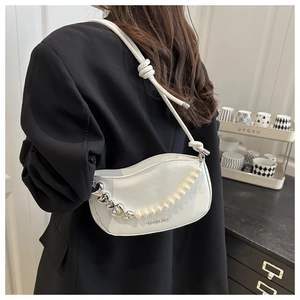 Close-up of white glossy saddle bag featuring pearl and heart metal chain detail
