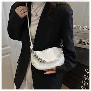 Detail of white half-moon bag with pearl and heart chain strap on black blazer
