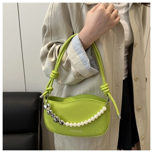 Detail of neon green saddle bag with heart silver chain and white pearl charms