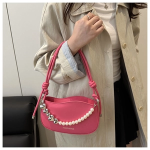 Detail of rose pink underarm bag with silver heart charms and pearl chain decoration