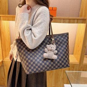 Vintage checkered tote bag with Z-pattern and plush bear charm shown in a warm interior