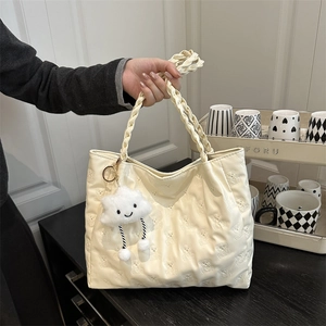Cream white tote bag with bear embossing, woven handle, and cloud charm held by a person