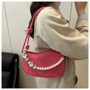 Detail of rose red underarm bag with silver heart and pearl decorative chain