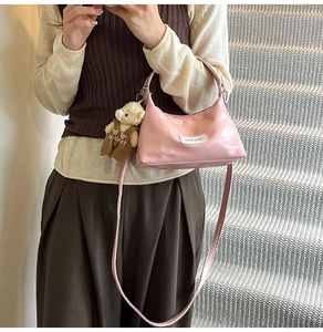 Pink glossy patent leather underarm bag featuring a cute teddy bear charm and logo tag