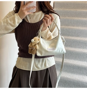 Close-up of cream cloud bag with glossy finish and cute brown bear plush charm