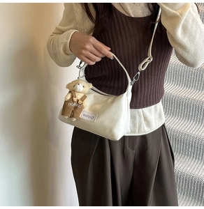 Glossy white patent leather underarm bag featuring a cute brown teddy bear plush charm