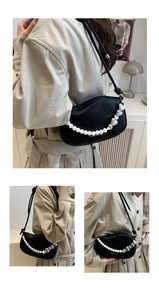Close-up of black leather underarm bag featuring pearl and silver heart chain detail