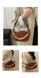 Detail of a brown crescent shoulder bag featuring a pearl and silver heart charm chain