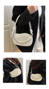 Detail of white saddle bag featuring pearl and silver heart charms with tied straps