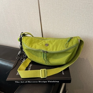 Detail van de avocado groen nylon halve maan crossbody tas met dambord charme op een bank