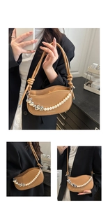 Detail of khaki underarm bag featuring pearl and silver heart chain with fashion logo