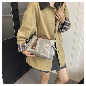 Gros plan d'un sac gris texturé avec bordure en cuir marron et étiquette de mode