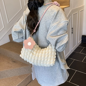 Sac nuage blanc avec bandoulière tressée rose et grand charm fleur dans un décor tendance