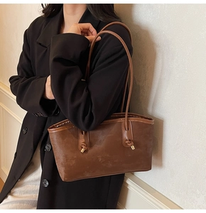 Close-up of deep brown suede tote bag with knotted strap and gold metal accents