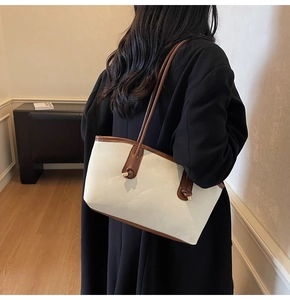 Detail of trendy white tote bag with brown knot strap on model in professional setting