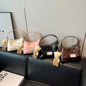 Glossy patent leather handbags in four colors with cute plush bear charms on a sofa