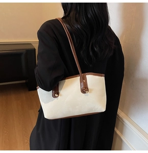 Detail of minimalist tote bag with cream leather and brown straps showing gold metal buckle