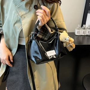 Fashionable black patent leather shoulder bag with a cute bear pendant and top handles
