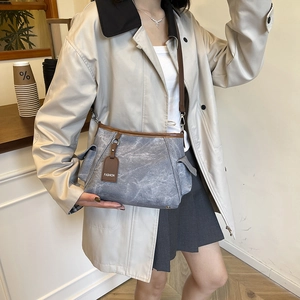 Sac bandoulière rectangulaire en toile grise avec finitions en cuir marron sur mannequin