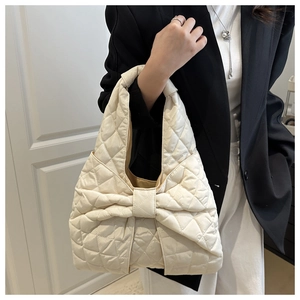 Detail of a beige quilted puffer bag with large bow and chic diamond stitch pattern