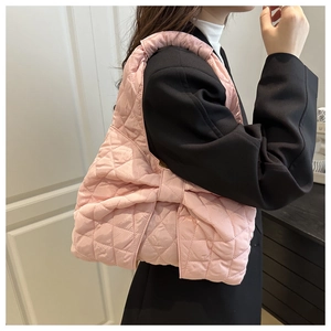 Detailed close-up of a pink quilted tote bag with a large bow, shown on a model
