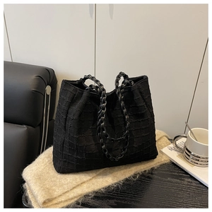 Macro detail of black quilted tote bag texture with stylish metal chain handles