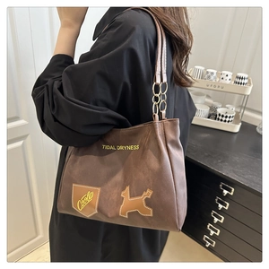 Detail of brown suede tote bag with metal chain strap and embroidery patches