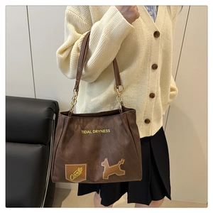 Detail view of large brown tote bag with metal rings and decorative dog patch