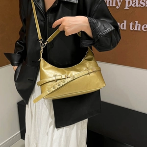 Sac bandoulière demi-lune doré métallisé avec ceinture décorative porté par un mannequin chic