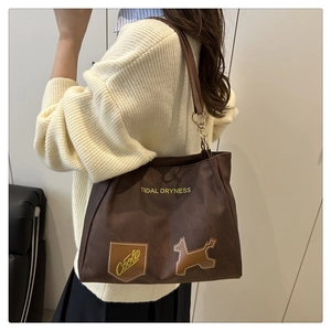 Close-up of brown tote bag with Tidal Dryness lettering and cute puppy patch detail