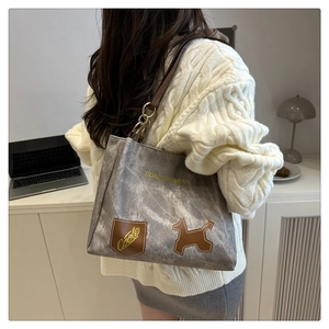 Detail of grey stone-washed tote bag with puppy patch and brown leather shoulder strap