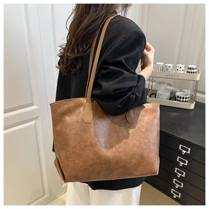 Detail of a brown leather tote bag with soft vintage texture and slim shoulder straps