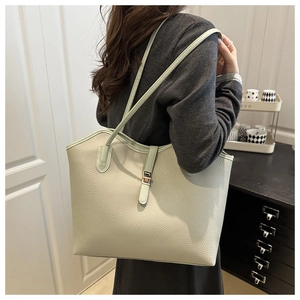Detail view of a pistachio green lychee pattern tote bag worn by a model in a cozy room