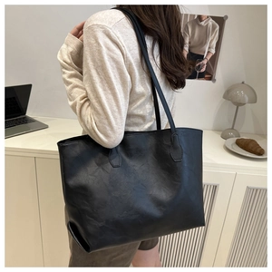 Detailed view of the large black tote bag showing premium pebbled texture on a model