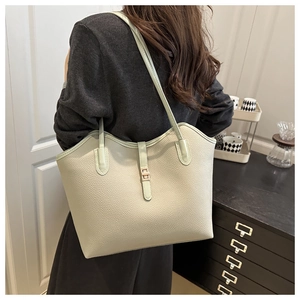 Detail of light green litchi texture leather tote bag with elegant gold metal buckle closure