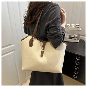 Detail of lychee pattern tote bag with brown contrast trim and metal buckle on woman
