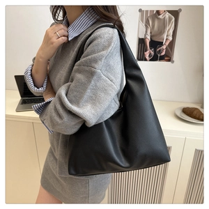 Close-up of black lychee grain leather tote bag worn on shoulder for daily commute