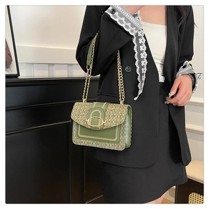 Sac bandoulière chic en tweed vert et cuir avec chaîne dorée porté par un modèle