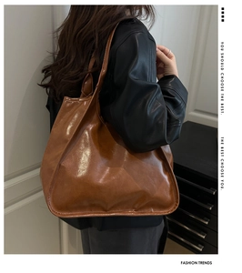 Close-up of a large brown glossy leather tote bag with wide straps for daily commuting
