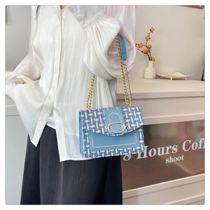 Détail du sac bandoulière en tweed bleu clair avec chaîne dorée et fermoir ovale
