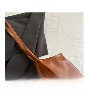 Detail view of brown leather tote showing fine texture and woven strap craftsmanship