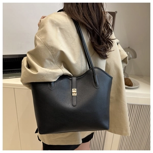 Detail of black litchi grain tote bag with gold swivel lock on a model shoulder