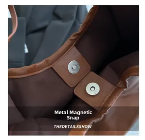 Detail of silver magnetic closure on brown lychee grain leather tote bag interior
