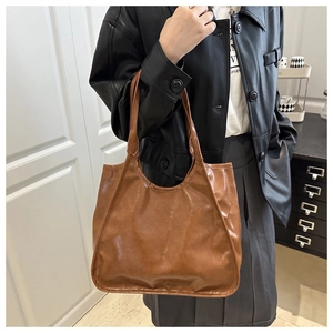 Brown faux leather tote bag showing spacious capacity and polished texture on model