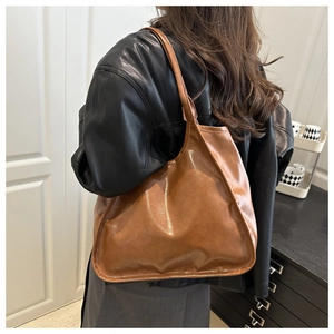 Close-up of brown oversized tote bag with vintage glossy texture and pleated PU leather